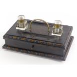 An early 20thC stained oak ink stand, with two square section glass wells, handle and a drawer, 29cm