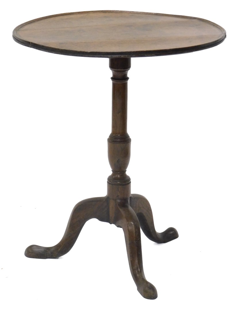 An early 19thC oak occasional table, the circular dished tilt top on a turned column and tripod base