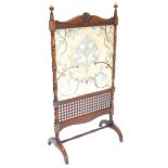 A late 19thC mahogany fire screen, the elaborate frame carved with a central tulip on turned support