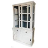 A cream painted cabinet, the top with a moulded cornice, with two sliding doors enclosing a grey pai