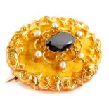 A Victorian yellow metal memorial brooch, of oval form set with a central garnet, flanked by seed pe