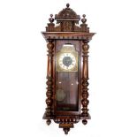 A Vienna wall clock, in a walnut case with part enamel and brass dial, flanked by a pair of pilaster