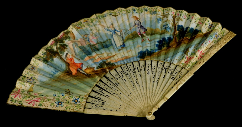 A 19thC continental fan, painted with figures within a landscape, a musician, etc, within a floral b