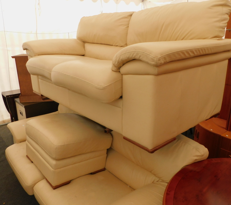 A pair of white leather two seater sofas, and an associated footstool.