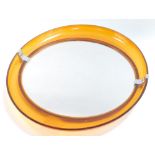 A 1970's orange acrylic framed elliptical wall mirror, inset circular glass, 50cm high, 43.5cm wide.