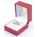 An 18ct white gold ruby and diamond ring, formed as three flower heads, interspersed with pairs of d