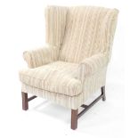 A George III style mahogany wingback armchair, with striped upholstery, on channelled legs, with H s
