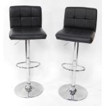 A pair of black leatherette and chrome plated adjustable breakfast bar stools.