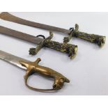 Three Eastern swords, to include a pair of short swords, each with a brass handle cast with a birds