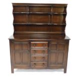 An Ercol elm dresser, the raised back with two plate shelves, the base with a moulded edge above fou