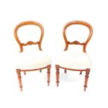 A pair of Victorian balloon back chairs, each with heavily carved horizontal scroll splats, and over