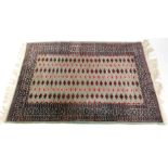An Afghan wool and silk mixed rug, turquoise ground decorated with seven rows of repeating guls, in