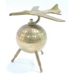 An atomic brass desk stand, modeled as an aeroplane atop a globe, 12.5cm wide.