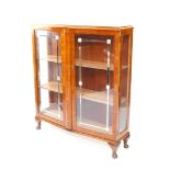 A walnut Art Deco style bow fronted display cabinet, with two glazed doors, each applied with mirror
