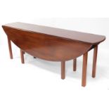 A mahogany wake table, the oval top with a moulded edge, on channeled legs, 209cm wide.