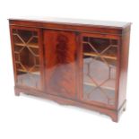 A mahogany bookcase, the top with a moulded edge, above two glazed doors, flanking a plain figured d