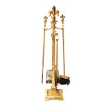 A set of 20thC brass fire irons, each on a stand, and with fleur de lys finial, on a square base, wi