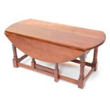 An oak drop leaf coffee table, with an oval top on turned supports, 115cm wide.