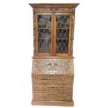 A late 19th/ early 20thC carved oak bureau bookcase, the top with a canted cornice, above a frieze d