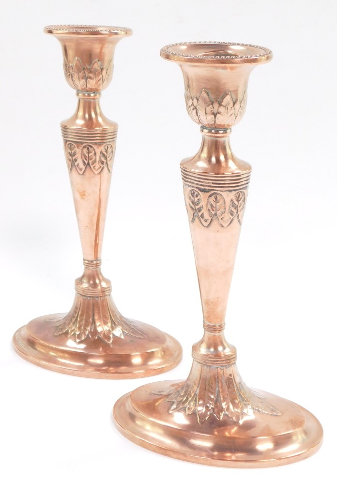 A pair of Adam style early 20thC copper candlesticks, embossed with acanthus leaves, 20cm high.