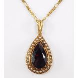 A Continental pendant, having pear cut garnet, surrounded by seed pearls, surmounted by fluted fitti