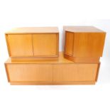 An E Gomme Ltd 1970's teak low corner unit, in three sections, with sliding doors, on a plinth, each