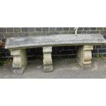 A reconstituted stone curved garden bench, the rectangular curved top on three scroll plinths, 49cm