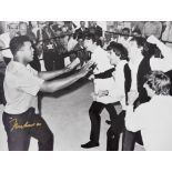 A framed black and white photograph Mohammed Ali with The Beatles, in the ring, bearing gold signatu