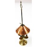 A copper and brass table lamp, the arched top converted to electricity, with a copper shade on brass