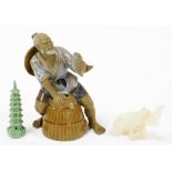 A 20thC Chinese figure of a fisherman seated on barrel holding fish, 20cm high, miniature tower orna