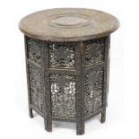 A Burmese Eastern hardwood table, on a hexagonal base with circular top, each engraved with flower w