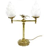 A brass table lamp, with two arm sconce with opaque glass shades, and a central bird on ball motif,