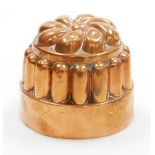 A Victorian copper jelly mould, the top with flower design, on reeded supports, on a circular base,