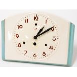 A vintage ceramic Junghams wall clock, with two cross arrowed detailing and clock key, on a turquois