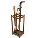 An oak four division stick stand, with an assortment of various walking sticks including an Oriental