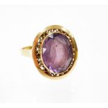 An amethyst set dress ring, the oval amethyst in rub over setting with floral etched raised border a