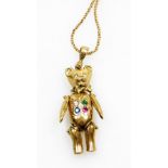 A 9ct gold bear pendant and chain, the articulated bear set with four semi precious gem stones, on a