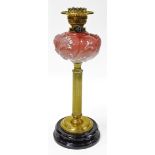 A Victorian opaque glass oil lamp, on a brass column, with pink floral reservoir on a stepped ebonis