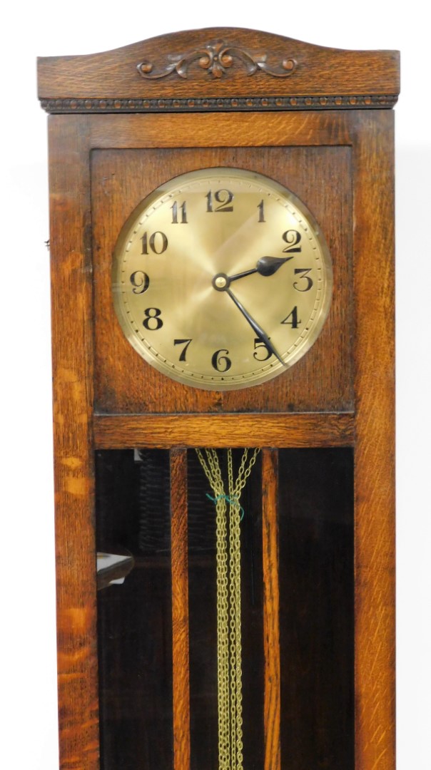 An oak cased longcase clock, with brass clock face, with floral banded arched top and mirrored centr