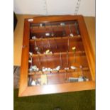 A mahogany hanging wall cabinet, with collection of ceramic thimbles and souvenir spoons.