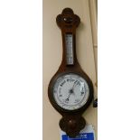 An early 20thC mahogany cased aneroid barometer, with carved floral motif ends, and white ceramic di