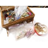 A wicker style basket containing a quantity of various costume jewellery, beads, necklaces, bracelet