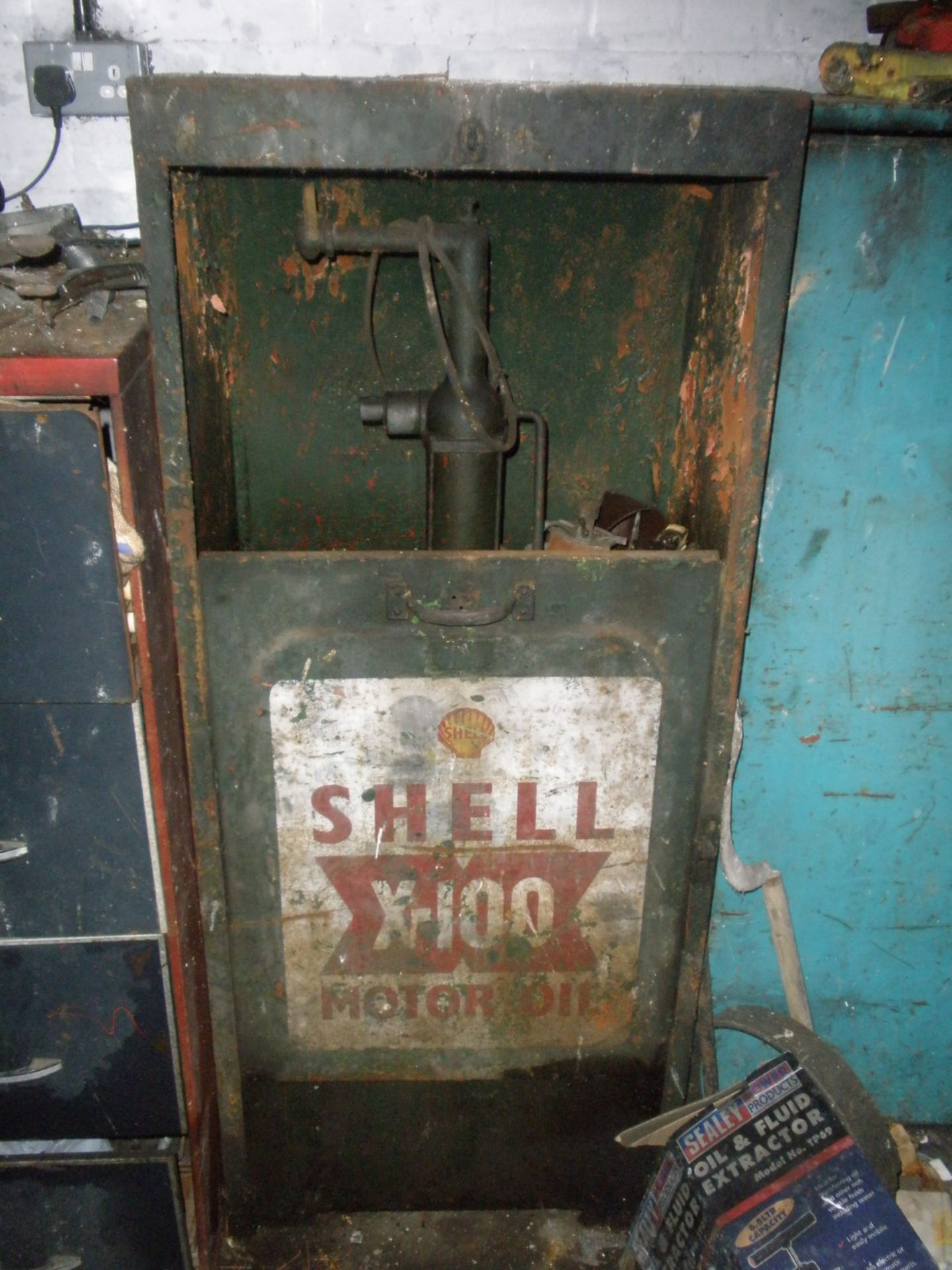 A vintage Shell X-100 motor oil dispenser cabinet.