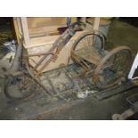 A vintage hand driven low tricycle carriage.