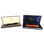 A Parker orange and black Duofold fountain pen, and a Pelican fountain pen.