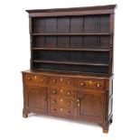 An early 19thC oak and mahogany dresser, the raised back with three plate shelves flanked by part tu