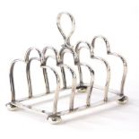 An Edward VII silver four division toast rack, with a teardrop handle, shaped divides, on four round
