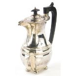 An early 20thC silver hot water jug, with an ebonised knop and handle, on four ball feet, hallmarks