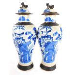 A pair of Chinese blue and white jars and covers, each with a blue painted detailing of flowers and