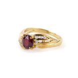 A dress ring, with central oval red paste stone with cz set shoulders, on a gold coloured band stamp